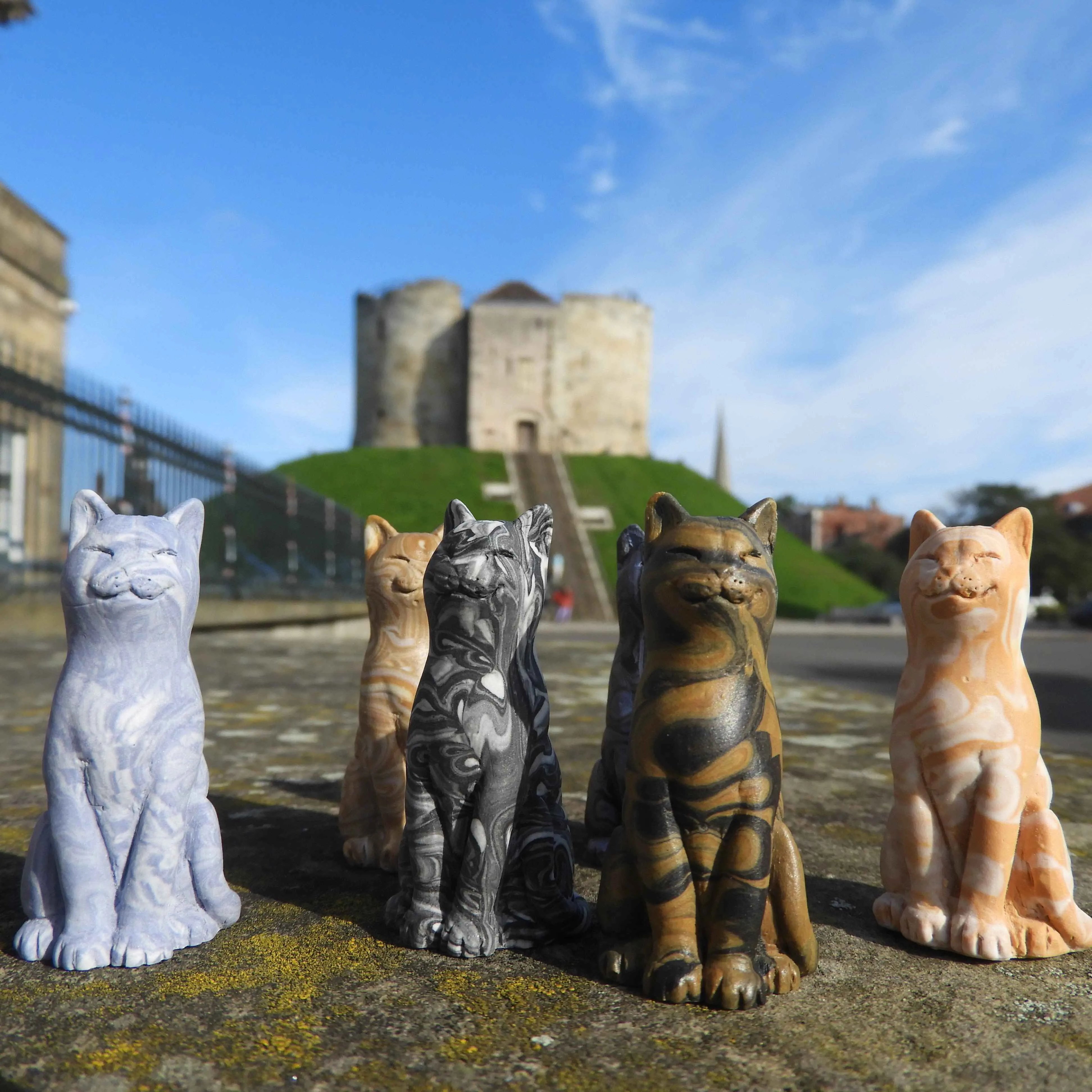 Cat sculptures from The Cat Gallery with Cliffords Tower in the background